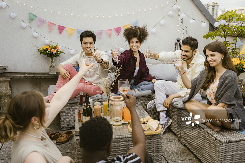 多种族朋友在阳台上举杯庆祝图片素材