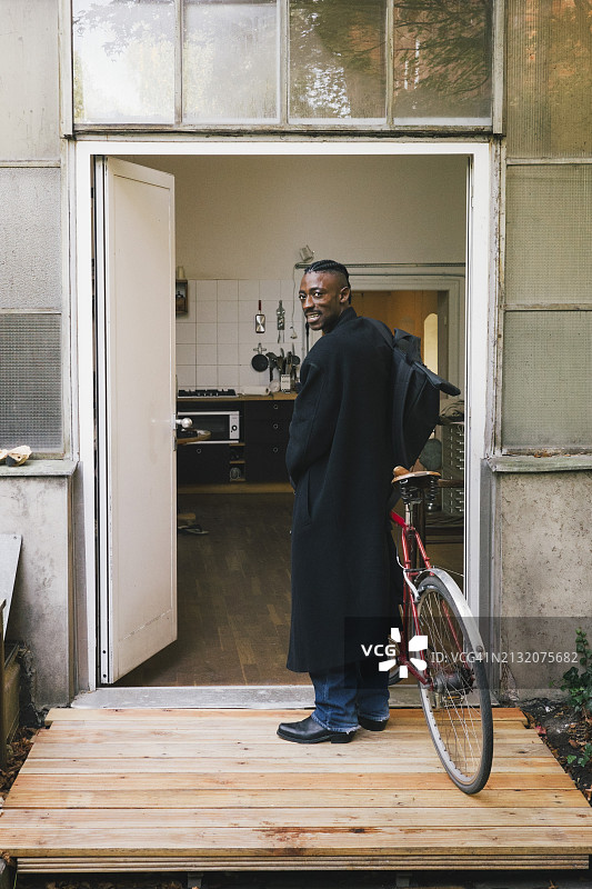 穿着大衣，在工作场所外骑自行车的商人图片素材