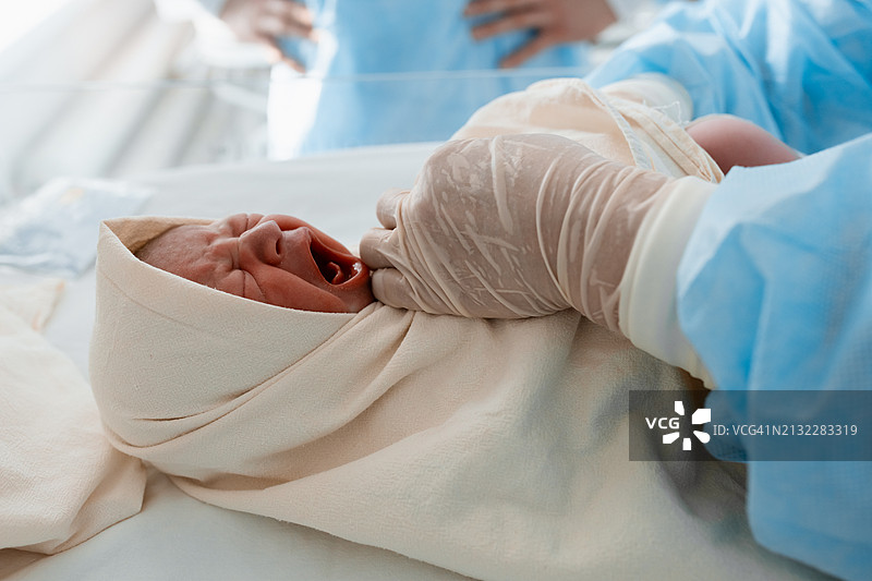 医生戴着手套教父母包裹新生儿，婴儿在哭图片素材