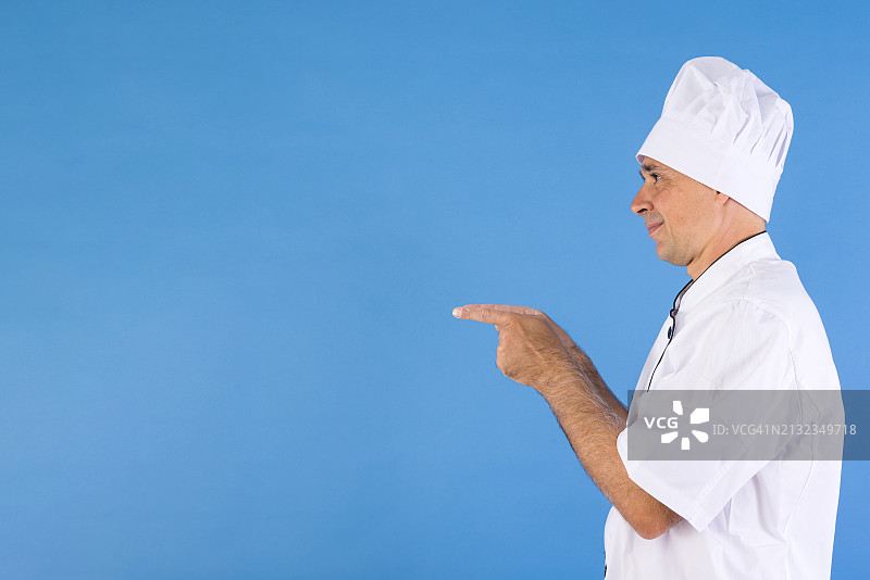 穿着厨师服的男人指向一旁，蓝色背景，适用于餐厅、烹饪、菜单、快餐和美食图片素材