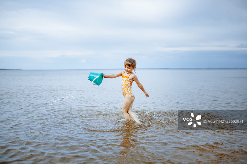 湖边休闲：儿童玩水桶，享受欢乐时光，促进早期发展图片素材