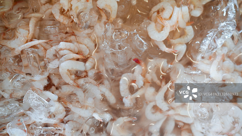 湿货市场出售的去头去壳鲜虾与冰块图片素材