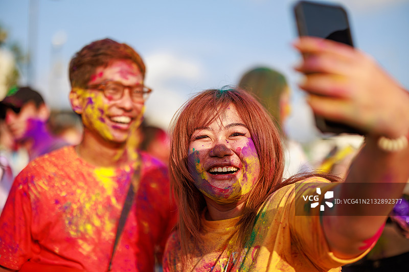 亚洲游客享受充满活力的胡里节，用手机捕捉丰富多彩的庆祝活动图片素材