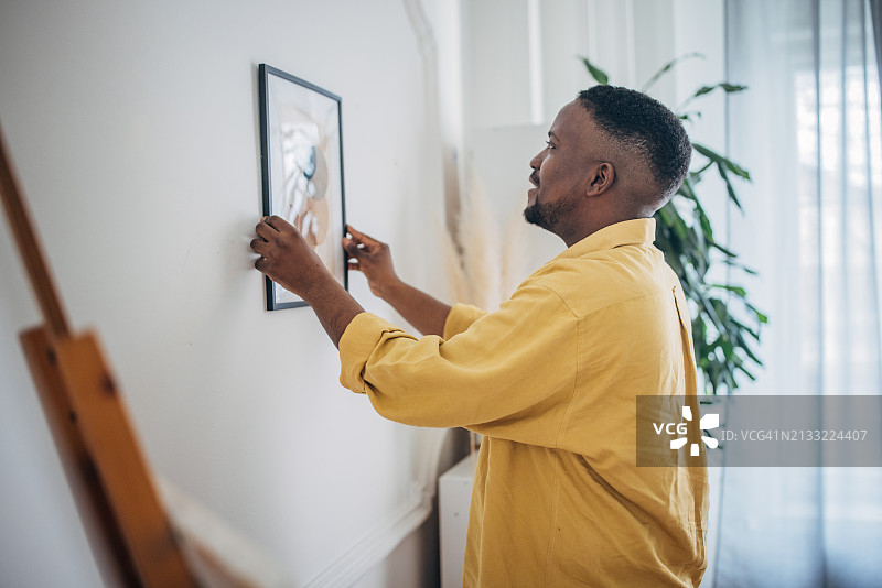 男子在家中悬挂艺术品图片素材