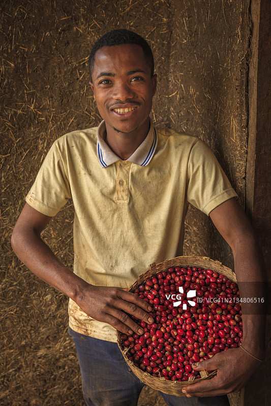 拿着满是咖啡樱桃篮子的非洲男人，东非图片素材