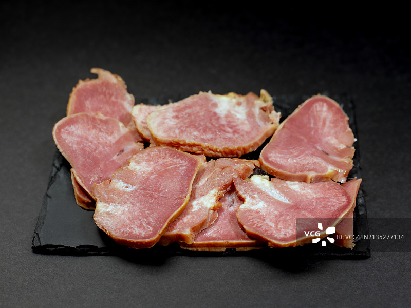 石板上切成薄片的烟熏猪舌图片素材