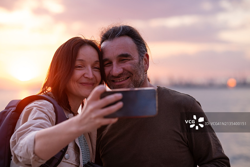 在堤坝上拍摄日落和自拍。情侣在塞萨洛尼基市中心散步图片素材