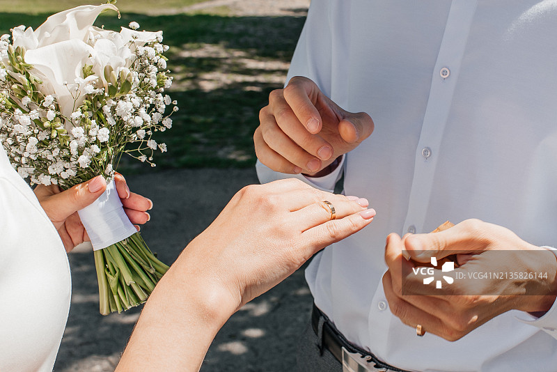 戴着结婚戒指的男女图片：年轻夫妇在婚礼当天手牵着手图片素材