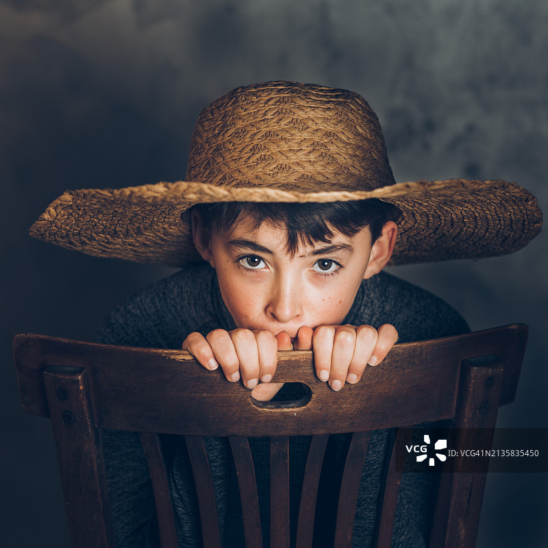 戴帽子坐在椅子上的男孩肖像图片素材
