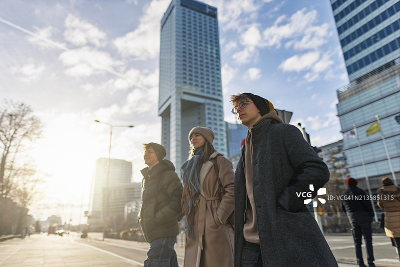 阳光明媚的冬日，青少年在华沙市中心散步图片素材