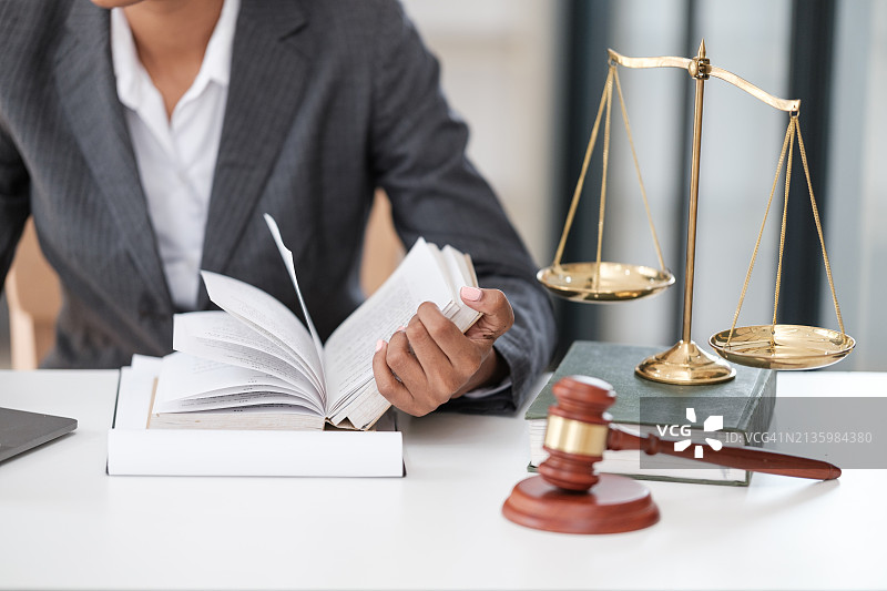 律师在办公室的办公桌旁看书的腰部特写图片素材