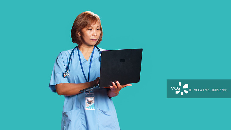 女医生站在蓝色背景前，拿着剪贴板图片素材