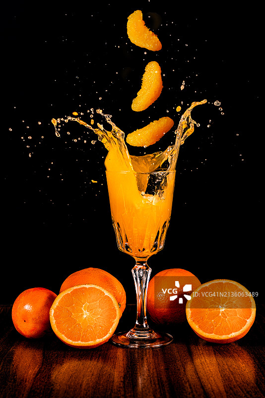 黑色背景下玻璃杯中橙汁特写图片素材