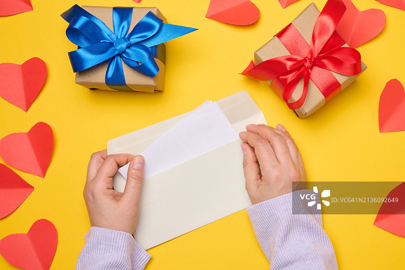 女人在黄色背景上拿着礼品盒图片素材