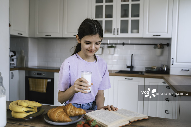美女在厨房读书并享用早餐图片素材