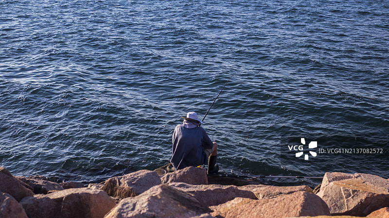 男子在平静的蓝色湖面上钓鱼图片素材
