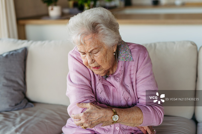 手臂疼痛的老年妇女，扶着她的胳膊肘。患有关节炎、骨质疏松症或类风湿关节炎导致关节疼痛和僵硬的老年妇女，因摔倒而骨折。图片素材