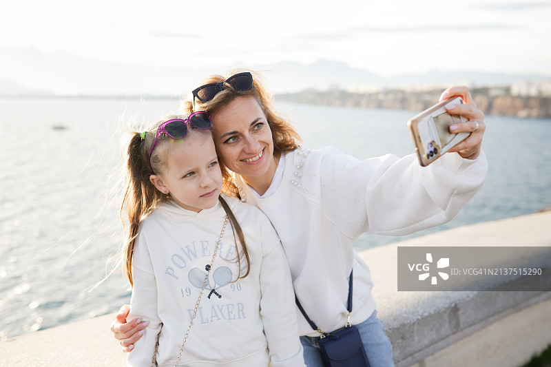 家庭亲情：中年母亲和女儿在土耳其安塔利亚拥抱、自拍和视频通话，家庭旅行时刻图片素材