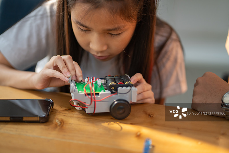 年轻女孩在男指导的帮助下尝试组装机器人套件，技术概念图片素材