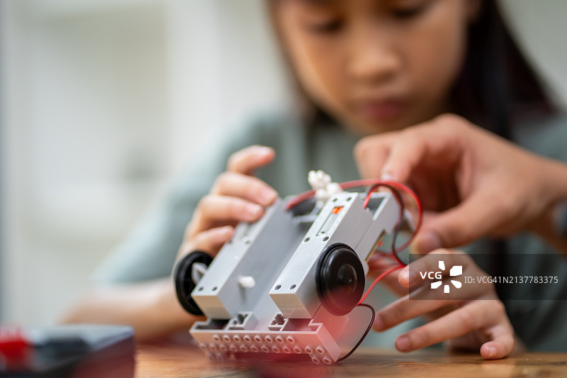 聪明女孩使用小型工具，通过平板电脑学习组装机器人，科技概念图片素材