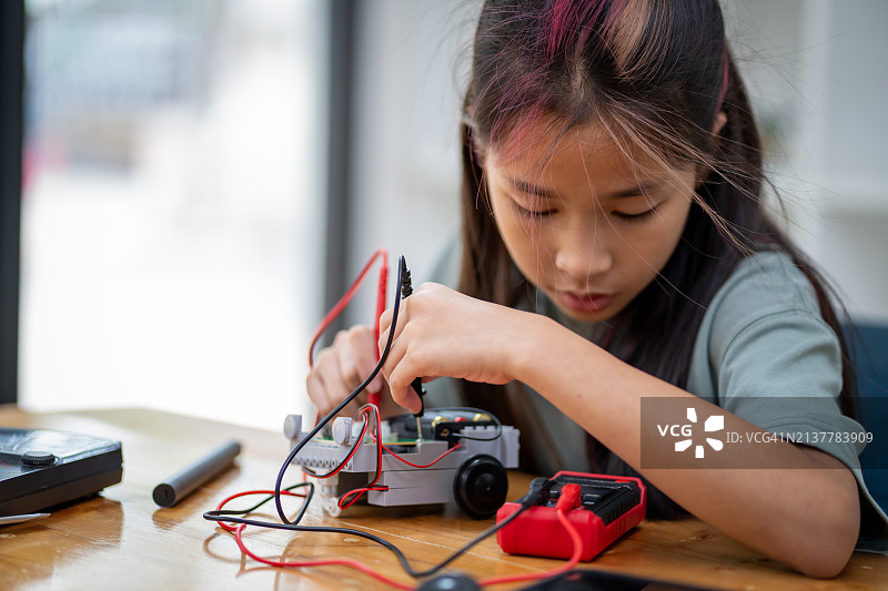 聪明女孩使用小型工具，通过平板电脑学习组装机器人，科技概念图片素材