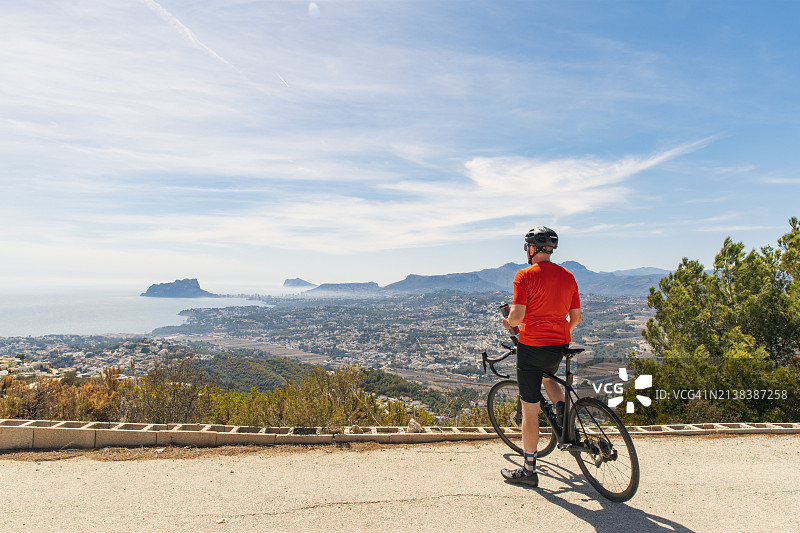 一位成熟的自行车手在阳光明媚的日子里欣赏西班牙海岸线的景色图片素材