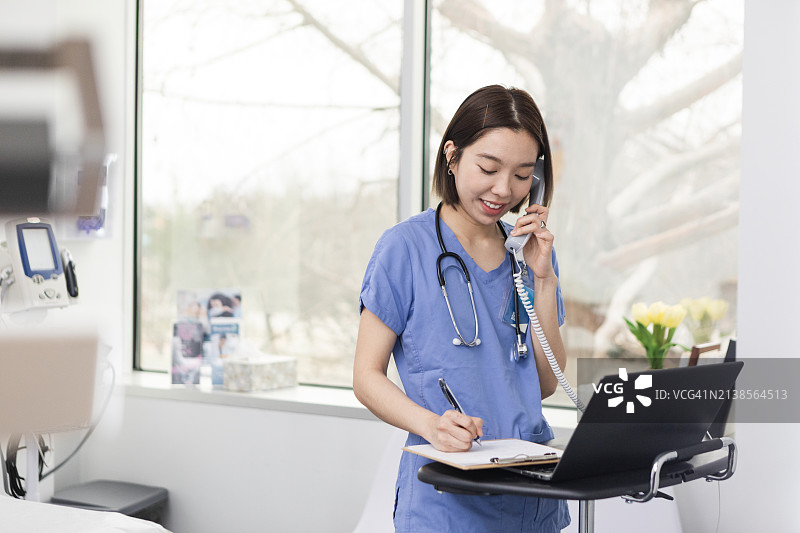 急诊室里，女实习生边打电话边做笔记图片素材