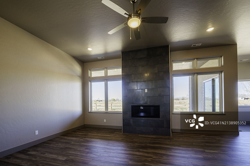 带有拱形天花板的现代高档住宅客厅，配有定制壁炉、观景窗和硬木地板图片素材