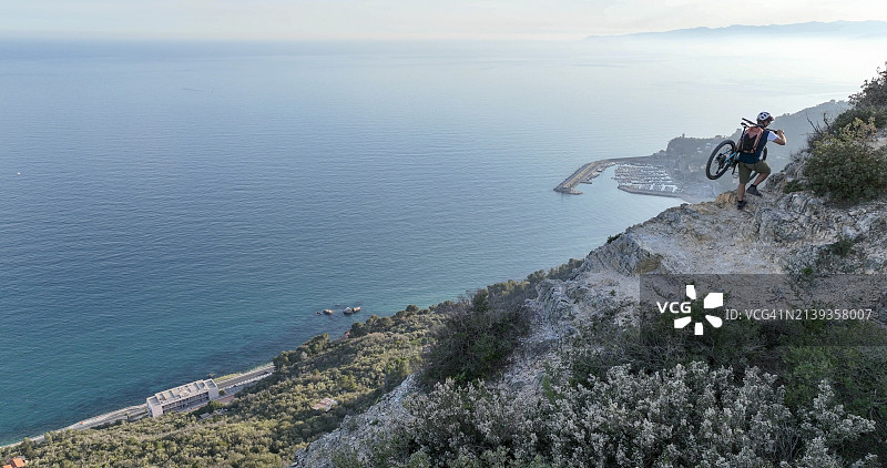 山地自行车骑行者扛车越海图片素材