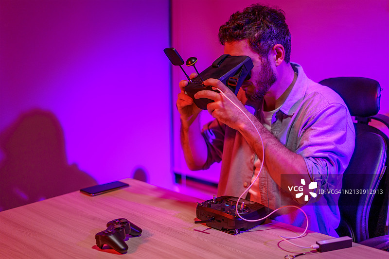 男人在家戴VR眼镜用遥控器操控小型无人机图片素材