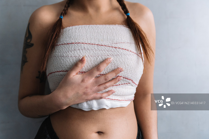 术后弯腰触摸胸部的女子（仅见背影）图片素材