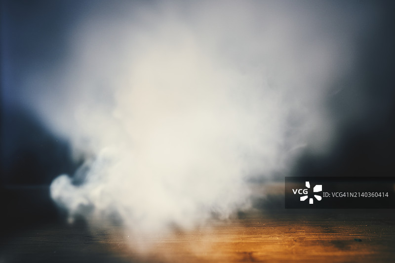 昏暗房间里木质表面上的漩涡烟雾图片素材