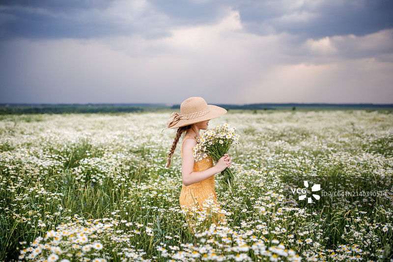 草甸的宁静：戴帽少女手捧雏菊花束，拥抱自然之美，享受健康图片素材