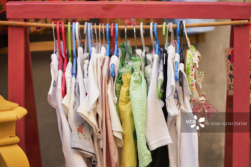 跳蚤市场上手工木制展示架上悬挂的彩色女孩服装图片素材