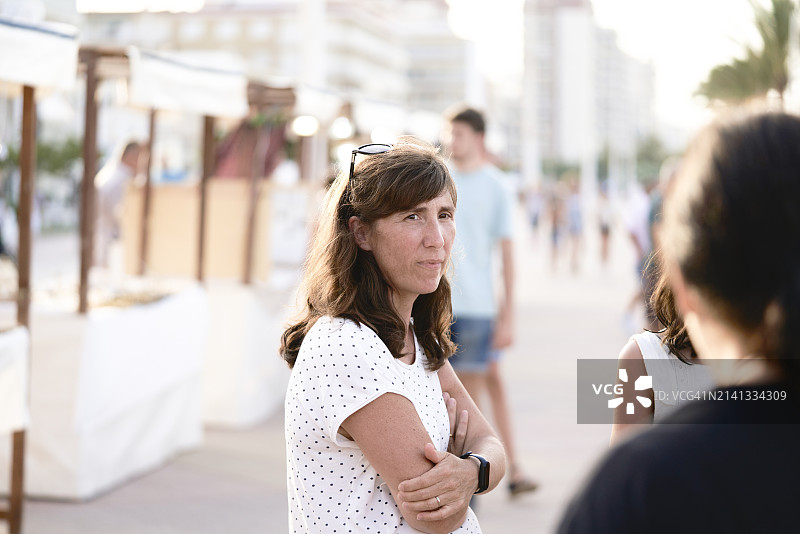 休闲装女游客在街上手臂弯曲站立的正面视图图片素材