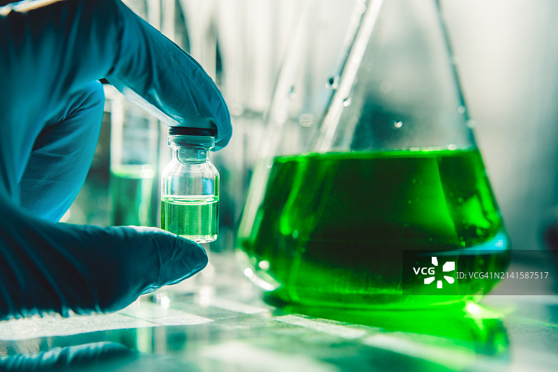 蓝色手套拿着绿色小瓶和绿色烧瓶图片素材