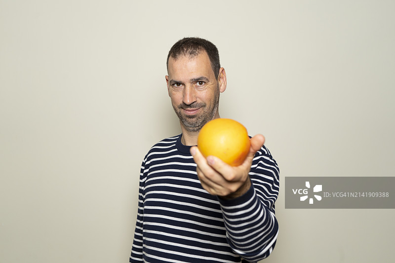 男人拿着橙子，背景为白色的画像图片素材