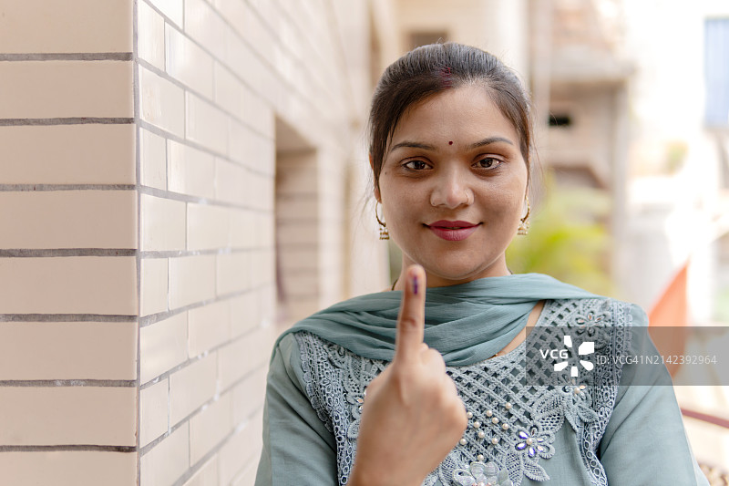 快乐的印度年轻女人在投票后伸出手指图片素材
