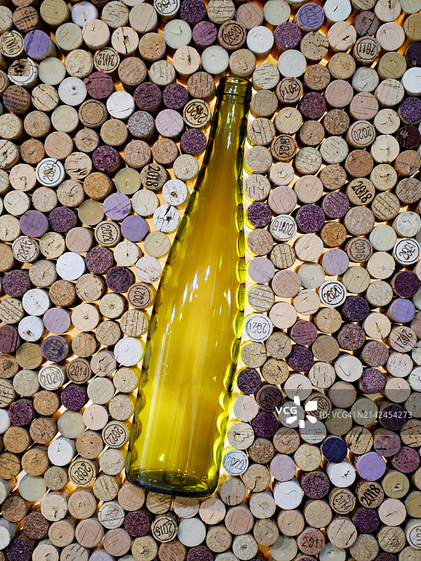 被软木塞环绕的黄色空酒瓶,部分软木塞被红酒着色,其他标有年份,法国巴黎工作室拍摄,人造光和自然色图片素材