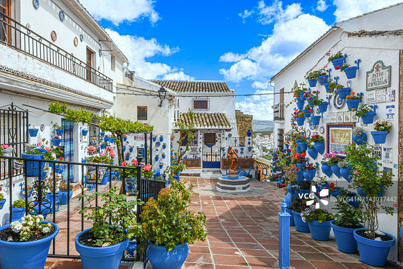 在西班牙安达卢西亚Subbetica的Iznajar，用鲜花盆精心装饰的安达卢西亚小白村庄（“pueblos blancos”）的传统白色公共广场图片素材