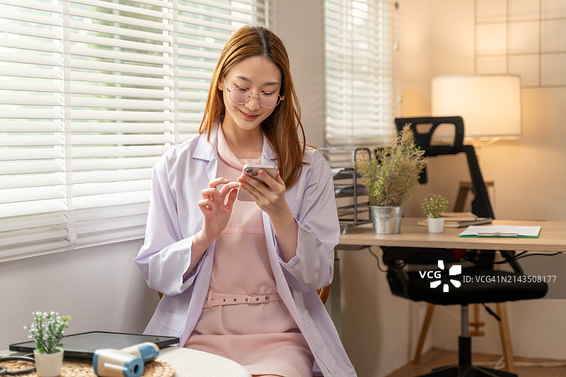 快乐的年轻女医生在办公室里用手机查看病人情况图片素材