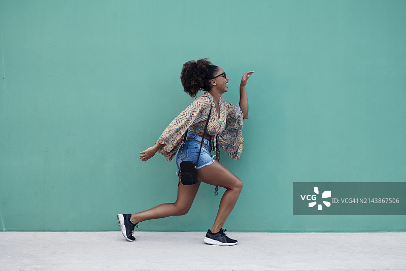 快乐的女人在绿墙前做手势图片素材