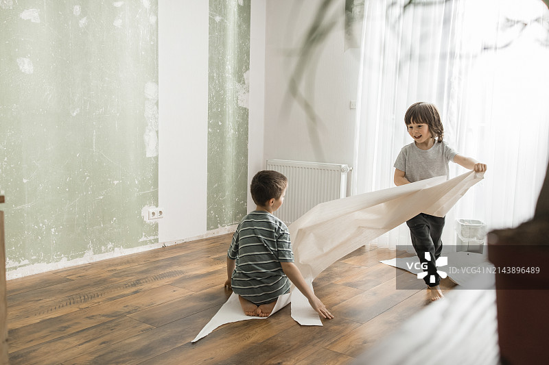 男孩拉着坐在墙纸上的弟弟在家玩耍图片素材