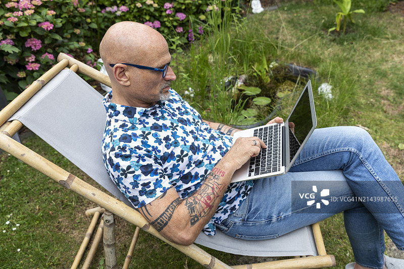 在花园里用笔记本电脑打字的自由职业者图片素材