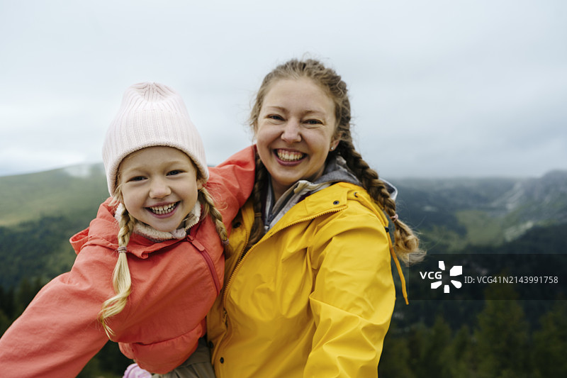 快乐的母亲背着女儿在山上图片素材