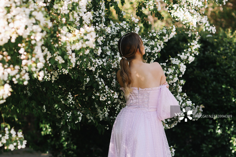 身穿优雅长裙的年轻女子在花园中漫步图片素材
