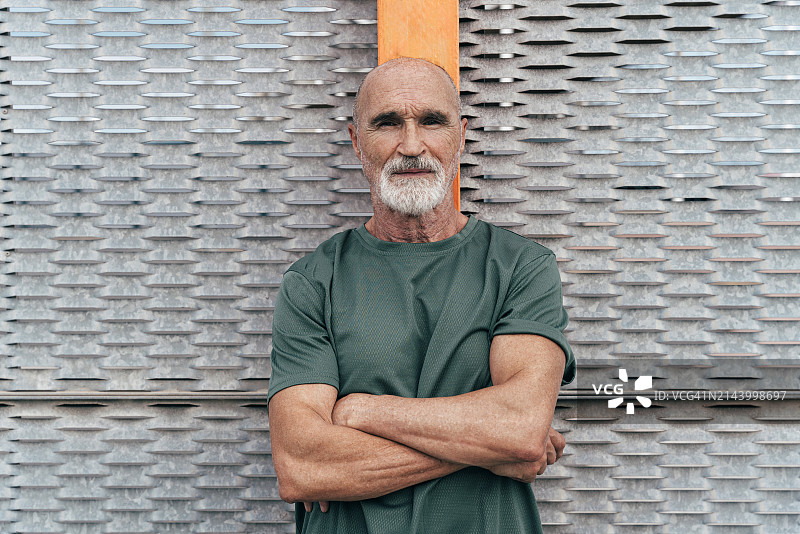 靠在栅栏上，双臂交叉的年长男人图片素材