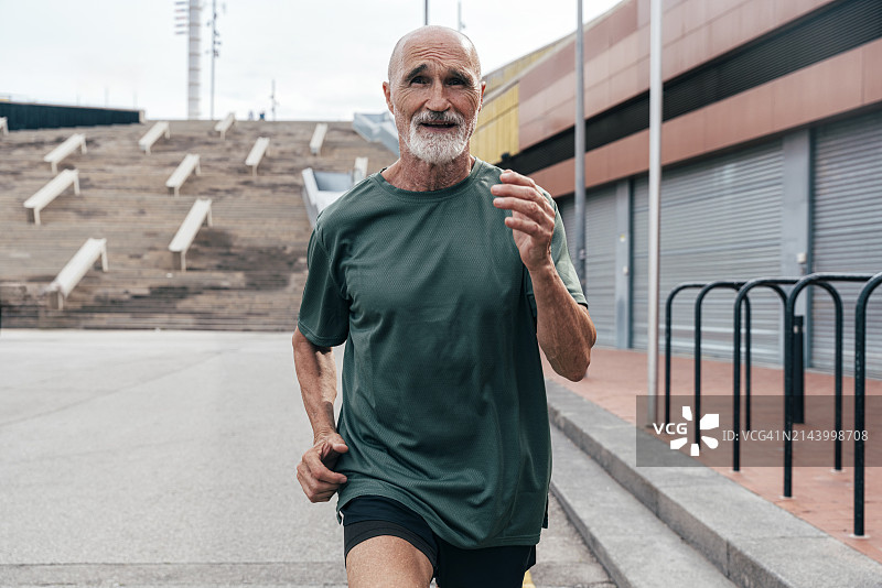 坚定的活跃老年男子在人行道上跑步图片素材