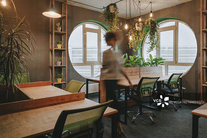 在办公室的办公桌间行走的模糊女商人图片素材