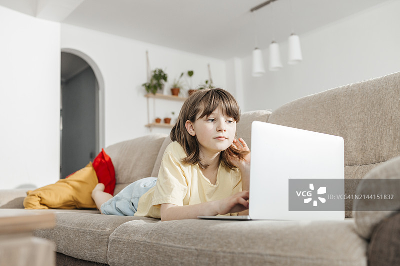 女孩在家躺在地上用笔记本电脑学习图片素材